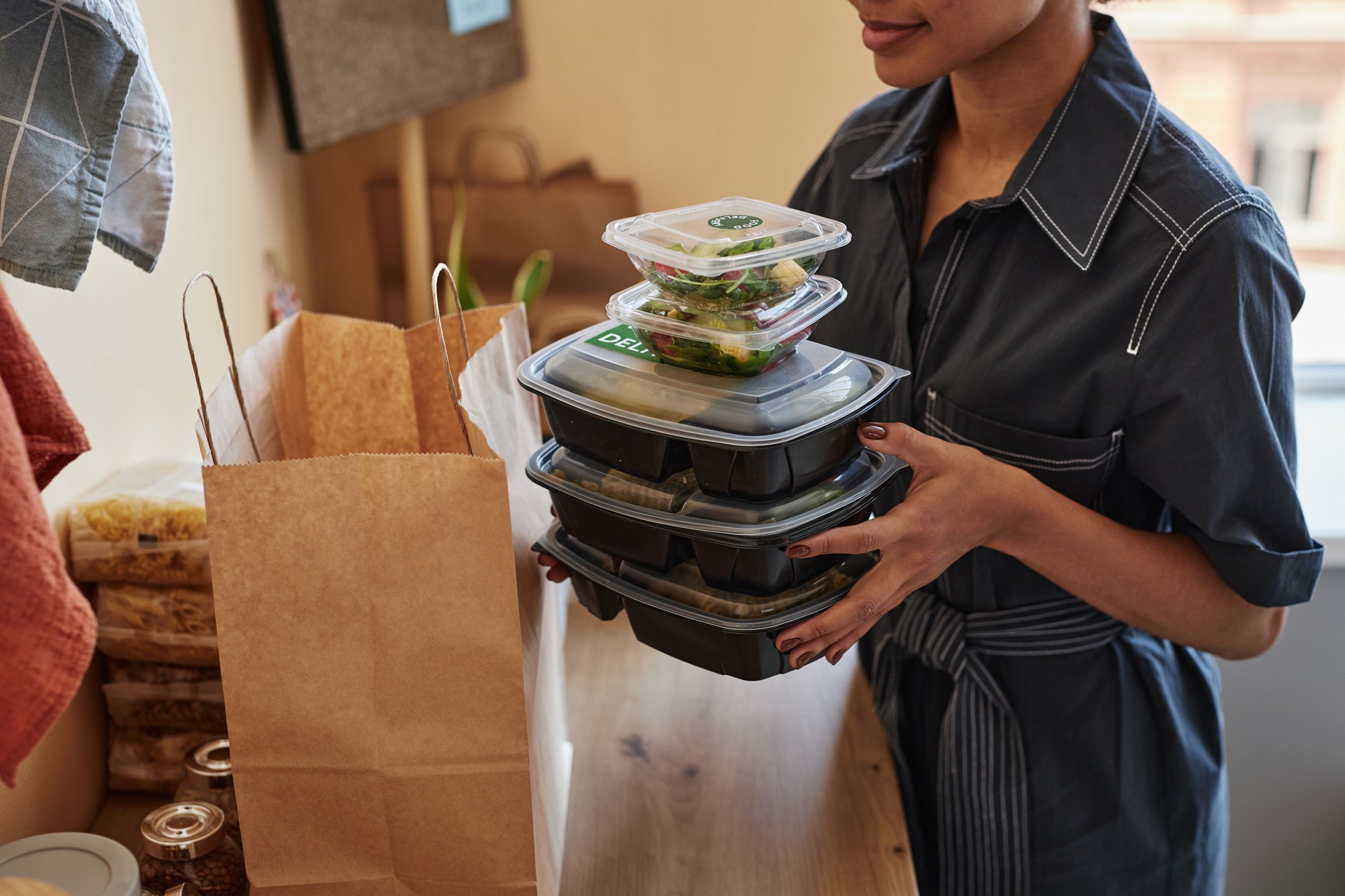 Young Black woman unpacking food delivery order at home kitchen